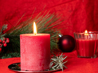 Red Christmas candle and Christmas decorations on a red background.