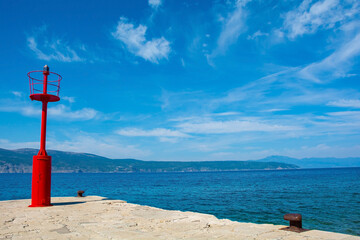 The red lighthouse on Glavotok pier during late summer, Krk Island in Primorje-Gorski Kotar County, western Croatia

