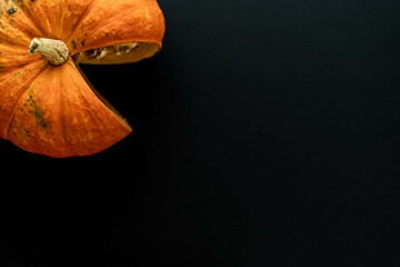 Flat composition orange pumpkin with a cut slice on a black background. A place for text.