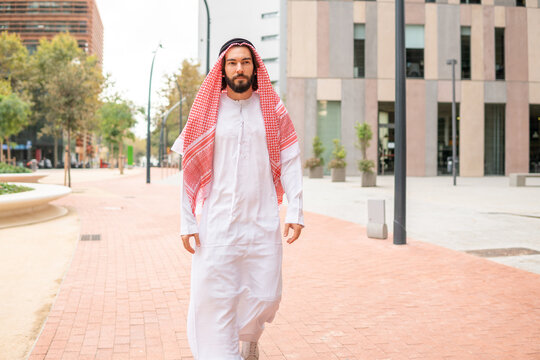 Handsome successful arab man sheikh wearing traditional clothes walking city street in Dubai