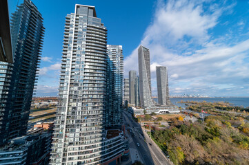 Obraz premium Drone Views of condos and Humber bay shores with brown trees tops Fall colours by Parklawn rd and lakeshore with blue skies and broken clouds 