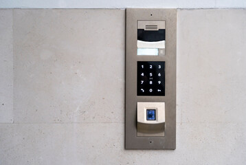 Matte metal intercom call panel with white digital buttons and fingerprint scanner on limestone...