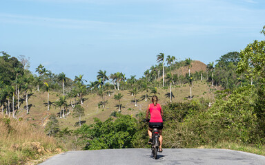 A cyclist exploring the hills of Cuba, surrounded by open spaces, palm trees, and nature, reflecting adventure and freedom.