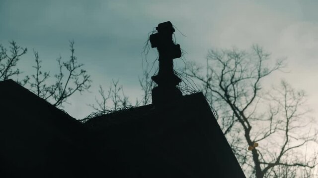 Stone Cross on an ancient tomb silhouetted against a dramatic sky in fall winter. Shot taken on the cemetery Alter Luisenstadt Kirchhof in Berlin