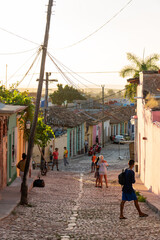 Evening light casting a golden glow on a charming street in Trinidad, Cuba, capturing daily life...