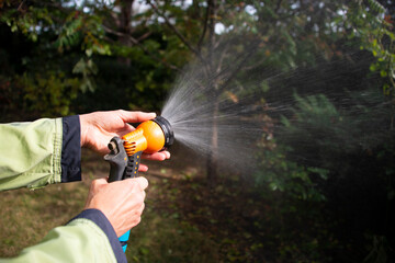 A man waters the lawn of the garden, the gardener takes care of the garden. Garden equipment: watering. Hose jet. Watering settings.