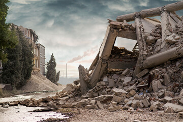 View on a collapsed concrete industrial building with smoking factory chimney behind and dark dramatic sky above. Damaged house. Scene full of debris