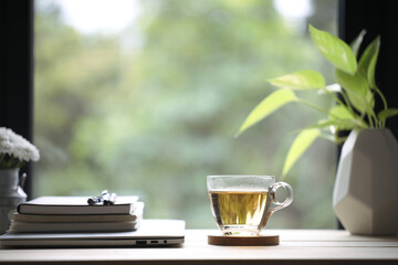 Hot tea glass and notebooks and plant pot in front of window