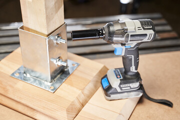 wrench with battery next to wooden furniture fittings