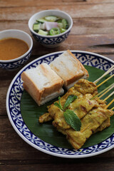 Local Thai food pork satay with oeanut dipping sauce isolated in wood background