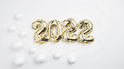 golden inflatable numbers 2022 on a background of white snow and white snow balls