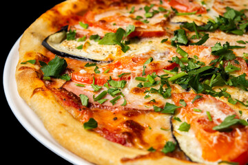 Delicious pizza close up, white plate on black background