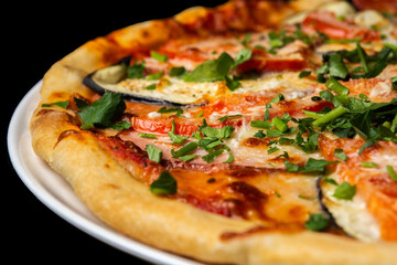 Delicious pizza close up, white plate on black background