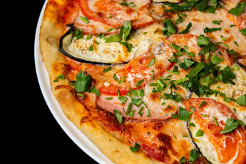 Delicious pizza close up, white plate on black background