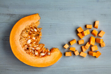 Fresh organic pumpkin slice and diced on a light blue wooden table