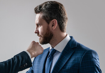 Professional man manager taking male fist punch in face grey background, uppercut - obrazy, fototapety, plakaty