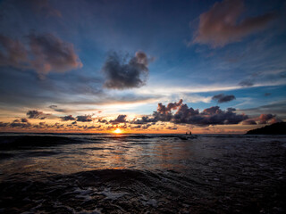 Fototapeta premium Beautiful sunset over the calm sea with cloud sky background. Sunset over tropical beach. Nature summer concept. Peak sunset over sea with yellow light reflect on sea water. Tranquil seascape.