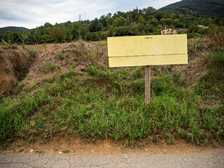 cartel informativo en un camino con los campos y las montañas de fondo