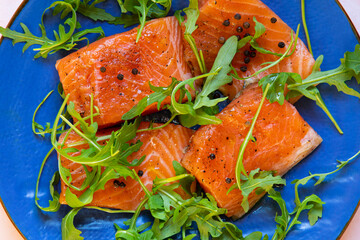 fillet of fresh salmon garnished with arugula salad, ready to eat , on a plate
