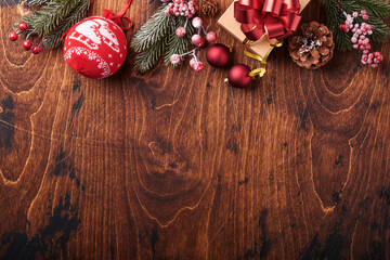 Christmas fir tree branches, Christmas balls, gift box, wooden snowflakes and stars on old wooden background for your xmas greetings. Top view with copy space. Christmas greeting card.