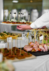 woman hands of a waiter prepare food for a buffet table in a restaurant