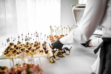 woman hands of a waiter prepare food for a buffet table in a restaurant
