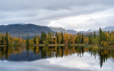 Tranquil Lakeside Reflection in Swedish Autumn. Perfect mirror image of the surrounding autumnal trees on the calm waters of a secluded Swedish lake.