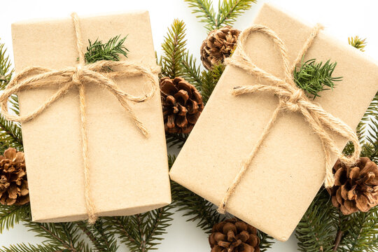 Beautiful Christmas background with two gift boxes, decorate with pine branch and pine cone over white background. Top view with copy space, flay lay.