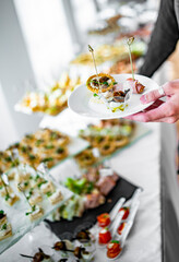 man hands take a snack and put it on plate. buffet in a restaurant