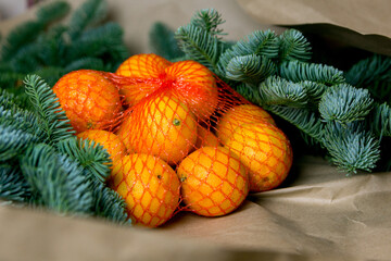 Christmas composition. Tangerines in a grid and branches of spruce on craft paper.