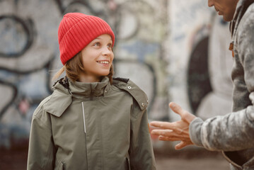 Portrait of smiling young boy talking with adult guy outdoor