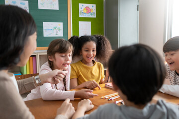 Pupils playing games with Asian female teacher together. Group of Diverse school kids having fun.