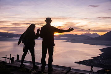 Fototapeta na wymiar Silhouette of a couple enjoying the sunrise from La Rostra Maya, Lake Atitlan, Guatemala