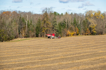 A a harvest machine sits near a rural roadside at harvest time with puffy white clouds.  Shot in...