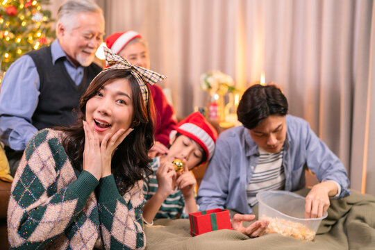 asian adult male give present box to hie parent in christmas holidays while using smartphone talking selfie photo happiness together at living room on sofa couch,family relation bonding home interior