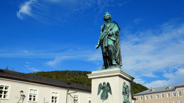 Das Mozart Denkmal steht auf dem Mozartplatz in der Altstadt von Salzburg unter blauem Himmel