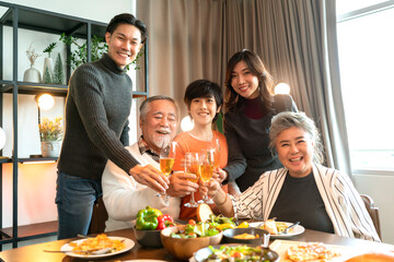 asian multi generation grandparent grandchild happiness joyful dinner together at home,holidays, celebration and people concept - happy friends with sparklers having christmas thanksgiving dinner - Powered by Adobe