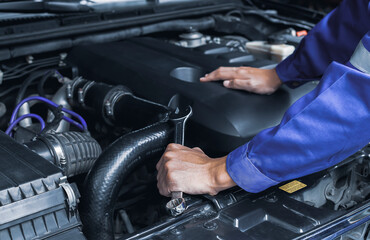 The mechanic works on the engine of the car in the garage, car repair service.