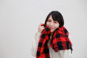 白い背景に赤いマフラーを身に着けている日本人女性