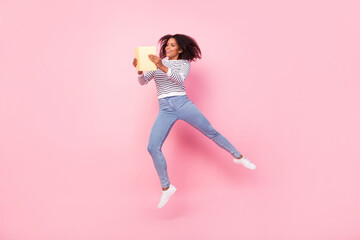 Full length portrait of attractive carefree girl hold book jump dream isolated on pink color background