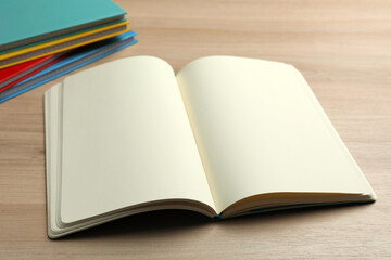 Open notebook and stack of planners on wooden table
