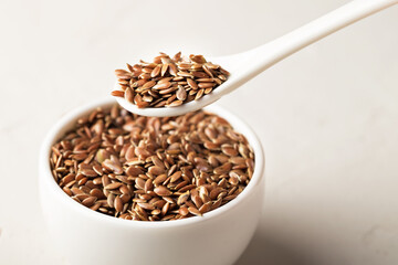 Flax seeds in a bowl on a light background. Selective focus. Close-up.