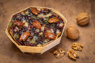 holiday rum cake with pecans, cherry and walnuts on a grunge bark paper