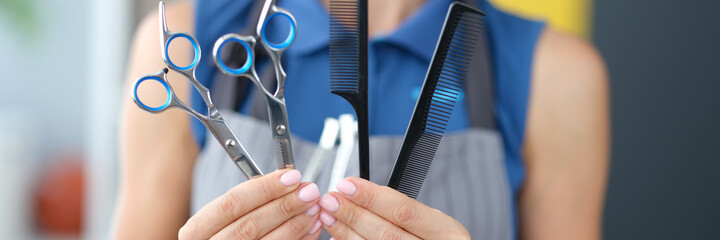 Woman hairdresser holding combs and scissors for hair cutting closeup