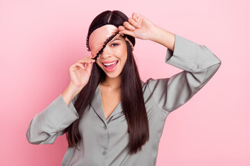 Fototapeta na wymiar Portrait of attractive cheerful girl touching blindfold waking up good mood isolated over pink pastel color background