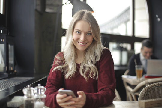 smiling young woman with smartphone in a cafe