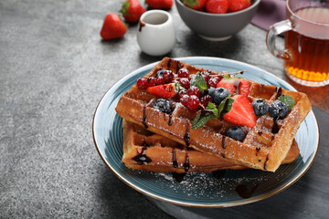 Delicious Belgian waffles with berries served on grey table