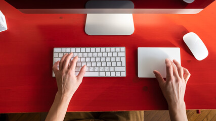 Female hands work with a keyboard and a touchpad, a mouse and a computer are nearby. Remote work. Contemporary workplace. 