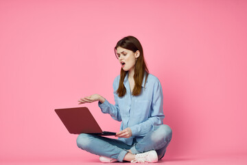 woman sitting on floor with laptop shopping entertainment pink background