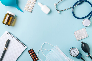 Medical concept, flat lay on blue background. Copy space in center. Stethoscope, tonometr, pills and other medical equipment on blue, top view - obrazy, fototapety, plakaty